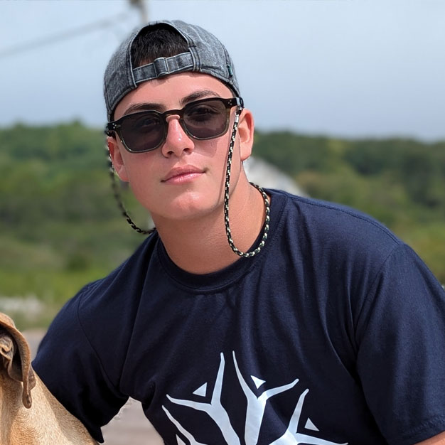 Portrait of Jose, a former Teen Camp participant, posing in the foundation's t-shirt in Galapagos. His testimonial focuses on personal growth and the elevation of values.
