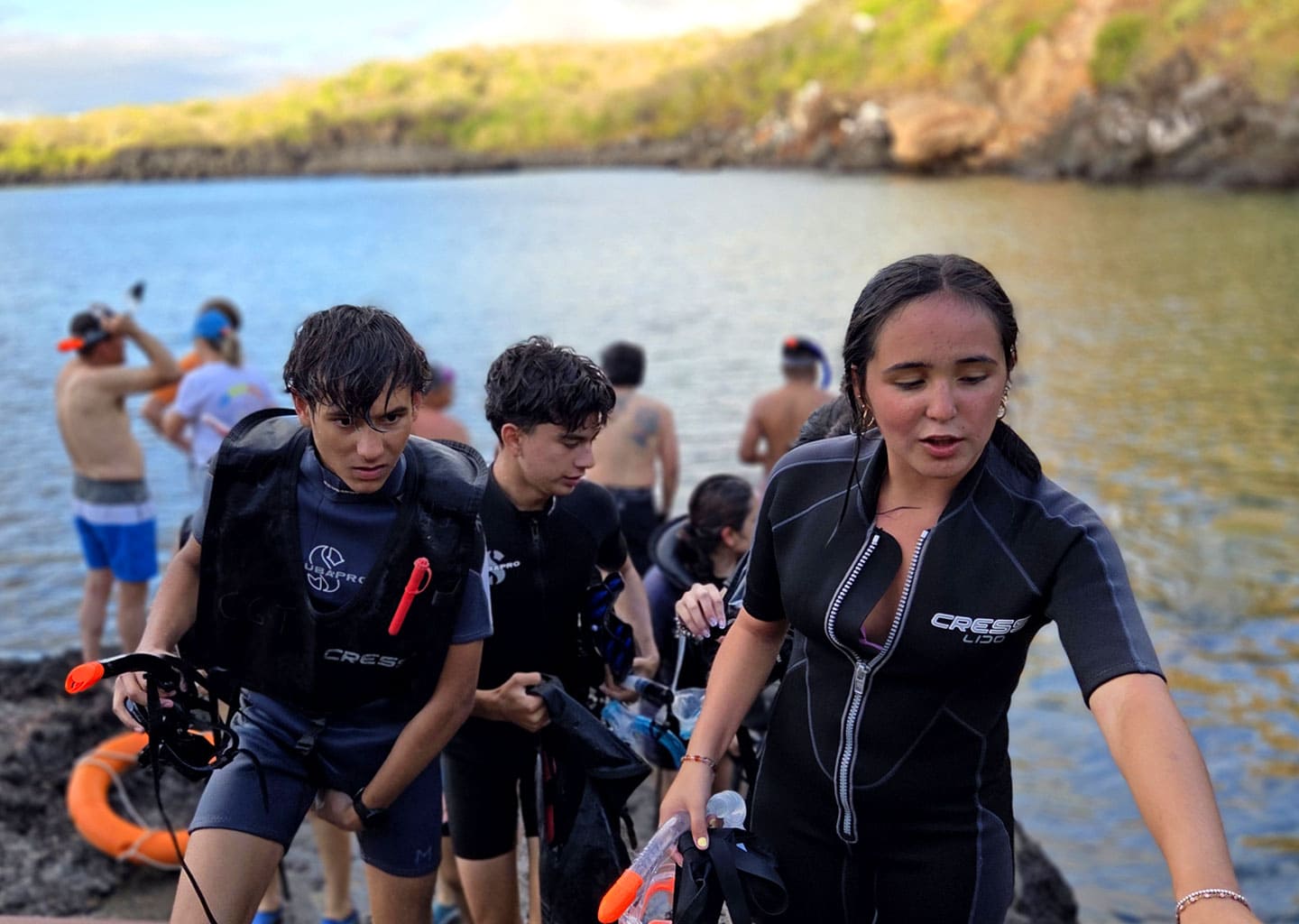 Youth in wetsuits and snorkel gear preparing to enter the water to explore marine life on the coasts of Galapagos.