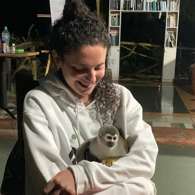 Teen participant smiling while holding a rescued squirrel monkey during Amazon Teen Camp Ecuador testimonial experience