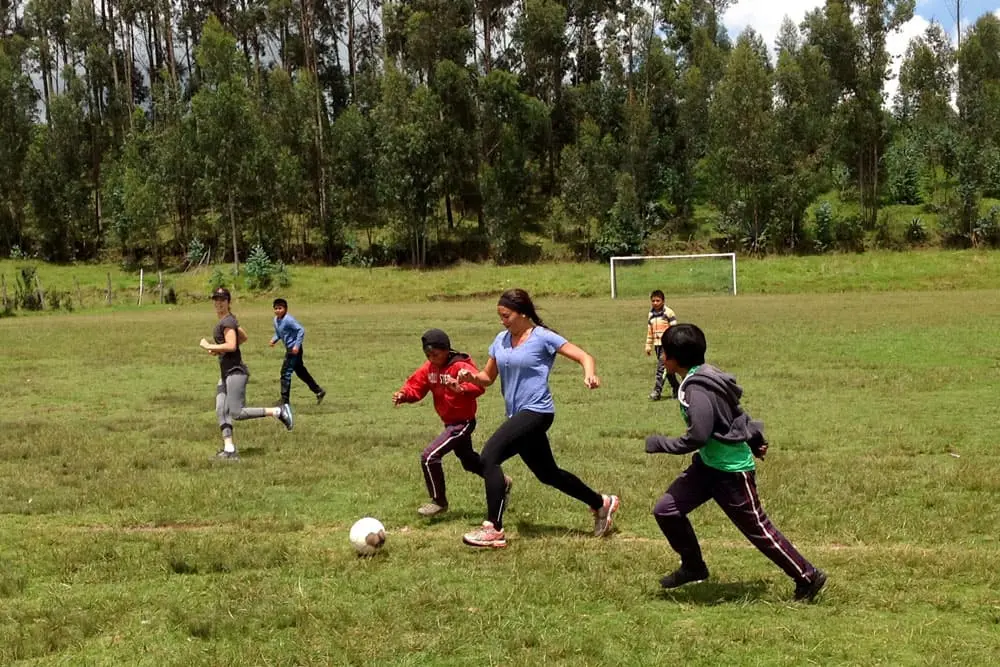 Teen participants playing soccer with local children during an Andes community program
