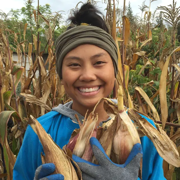 Teen participant smiling while harvesting crops in an Andean community in Ecuador